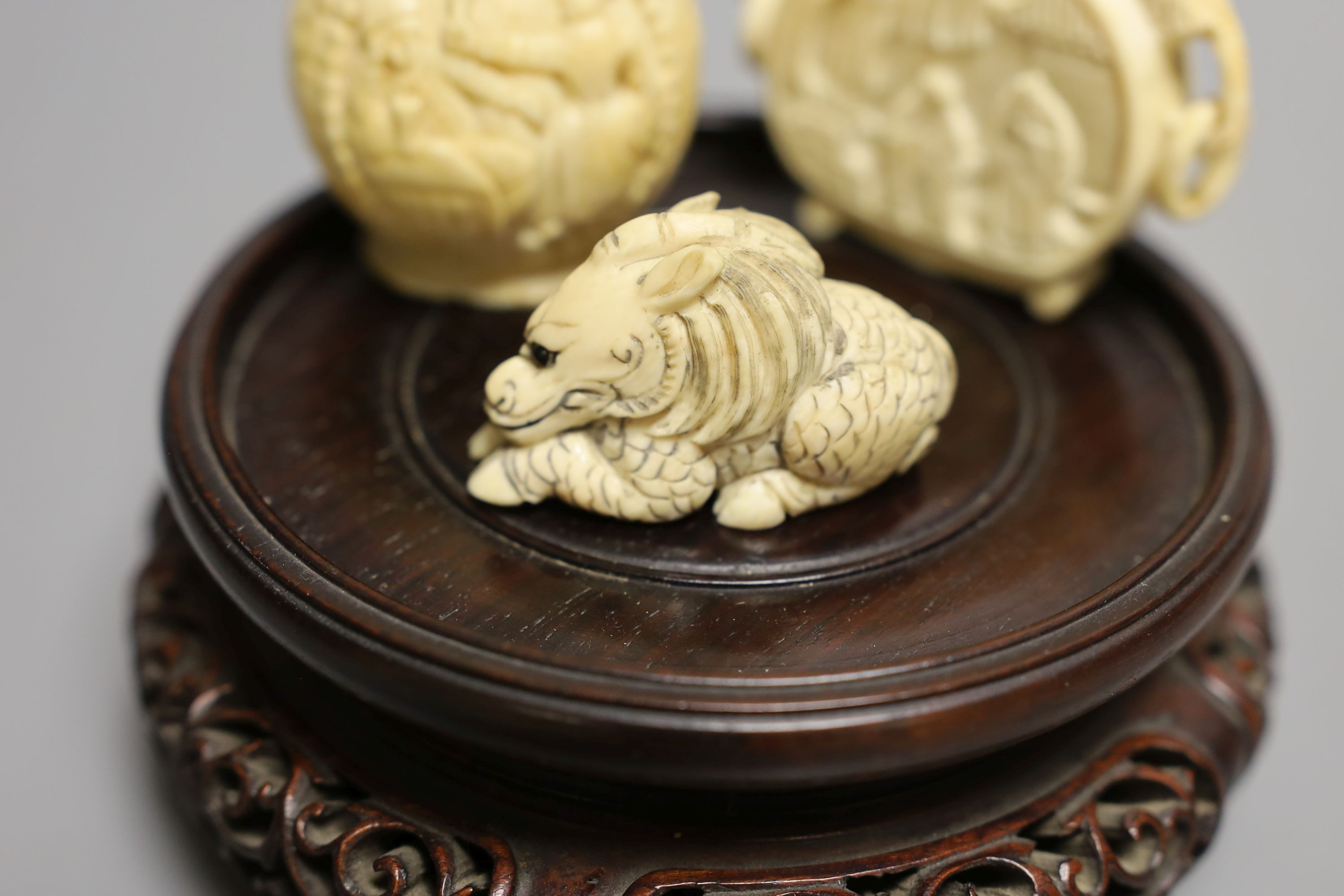 A 19th-century European carved ivory snuff bottle, and an early 20th century Chinese ivory snuff bottle and an ivory Netsuke of a lion-dog and a Chinese hongmu stand (4)